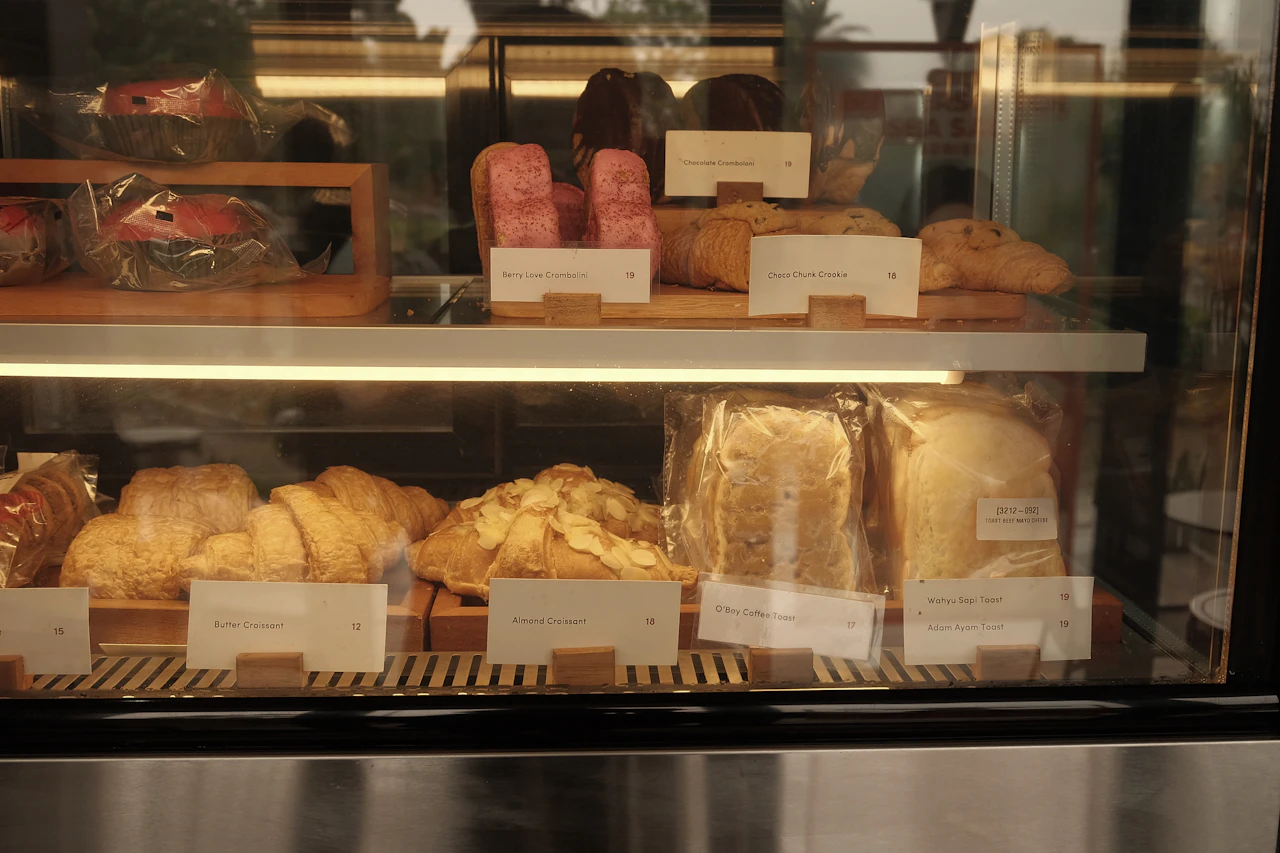 Vitrina de panadería llena de panes y reposterías con luz cálida